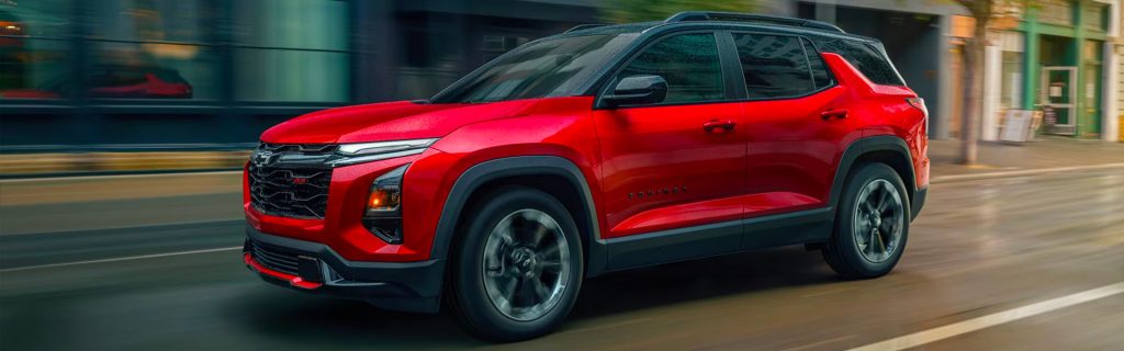 Red Chevrolet Equinox driving through a city street with motion blur.