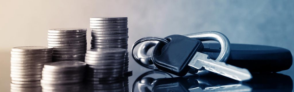 Car keys beside stacked coins representing vehicle financing.