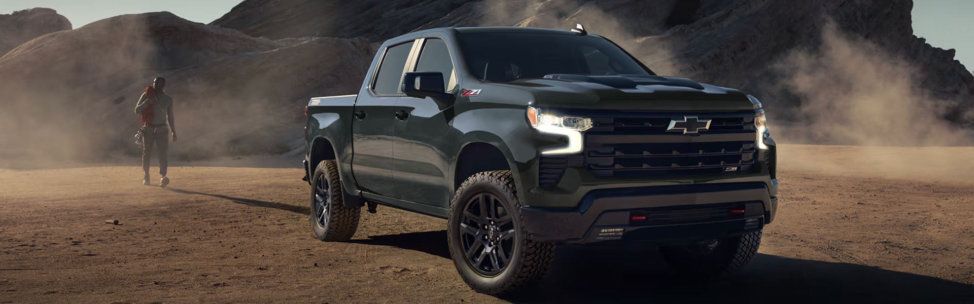 Black Chevrolet pickup truck parked in a rugged desert landscape with mountains in the background.