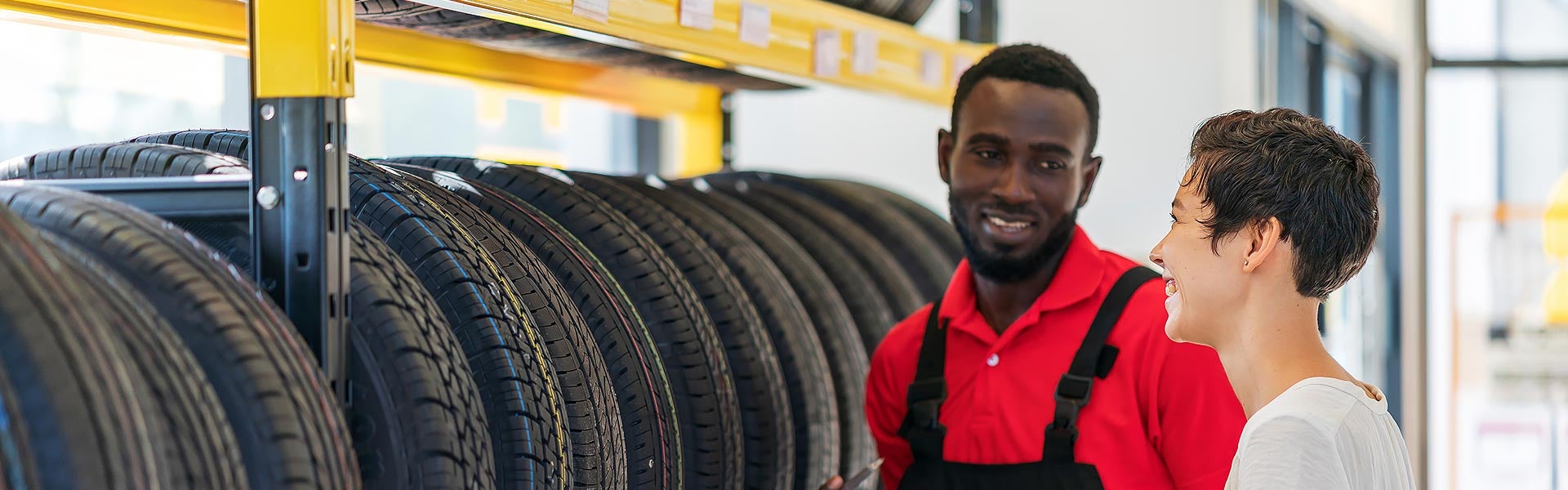 Automotive service employee assisting a customer while selecting tires at a tire shop.